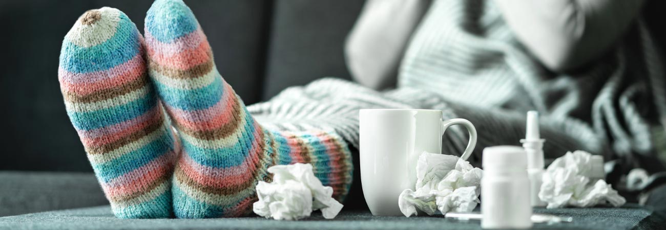 Person with flu sitting on couch with tissues