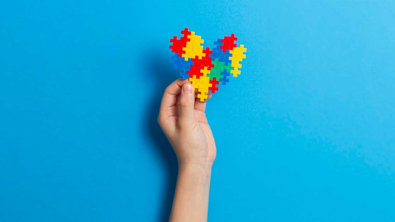 Child's hand holding up heart puzzle