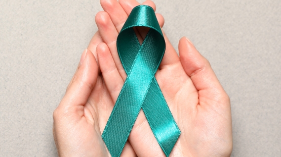 Green awareness ribbon held in hands