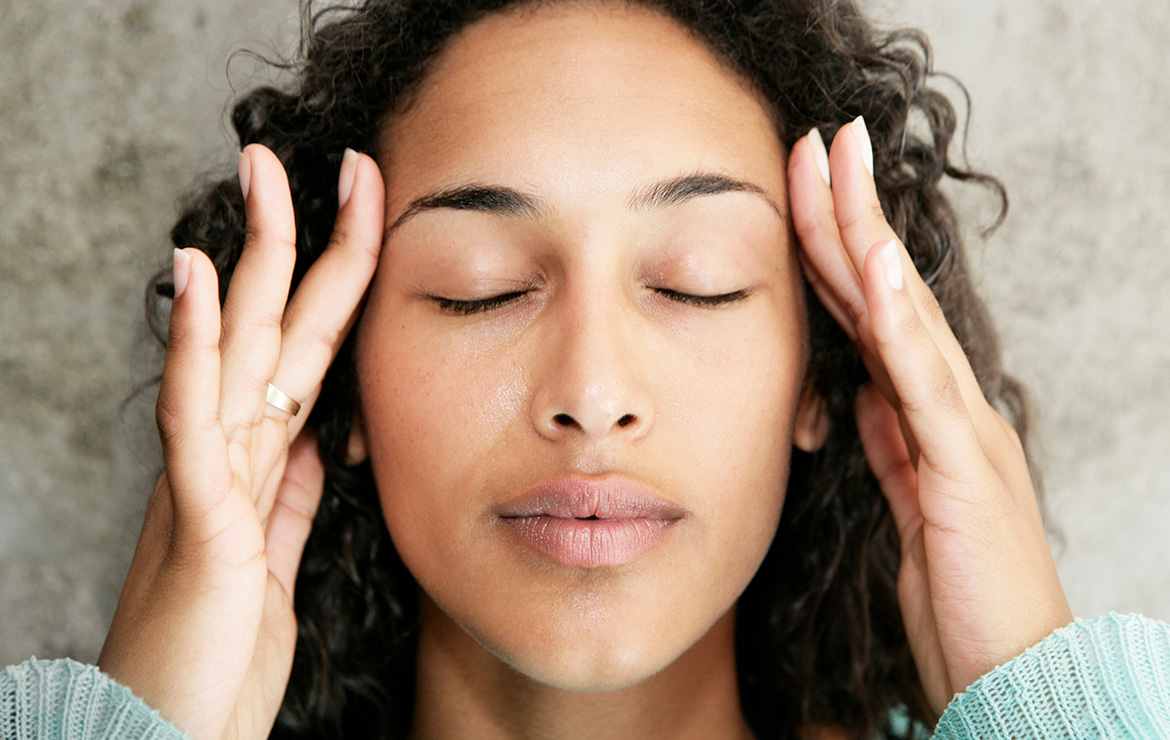 Woman placing hands on side of head with eyes closed