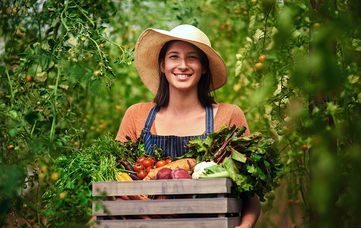 Smiling woman holding box of vegetables
