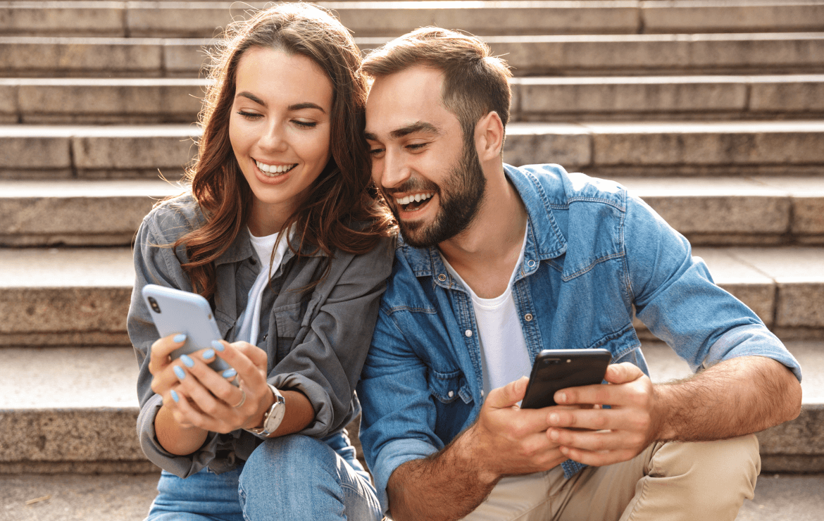 Young couple sitting on stairs viewing mobile smartphone together