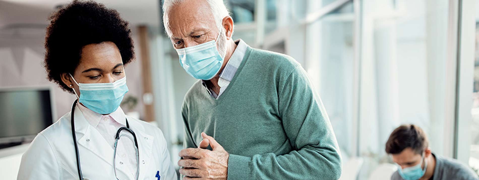 Doctor and male patient using touchpad while wearing masks