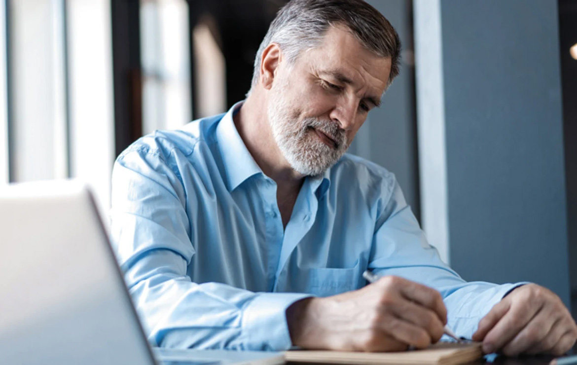 Elderly man writing on notebook paper