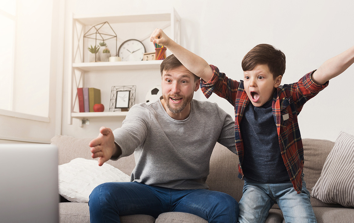 Father and son watching television with excitement