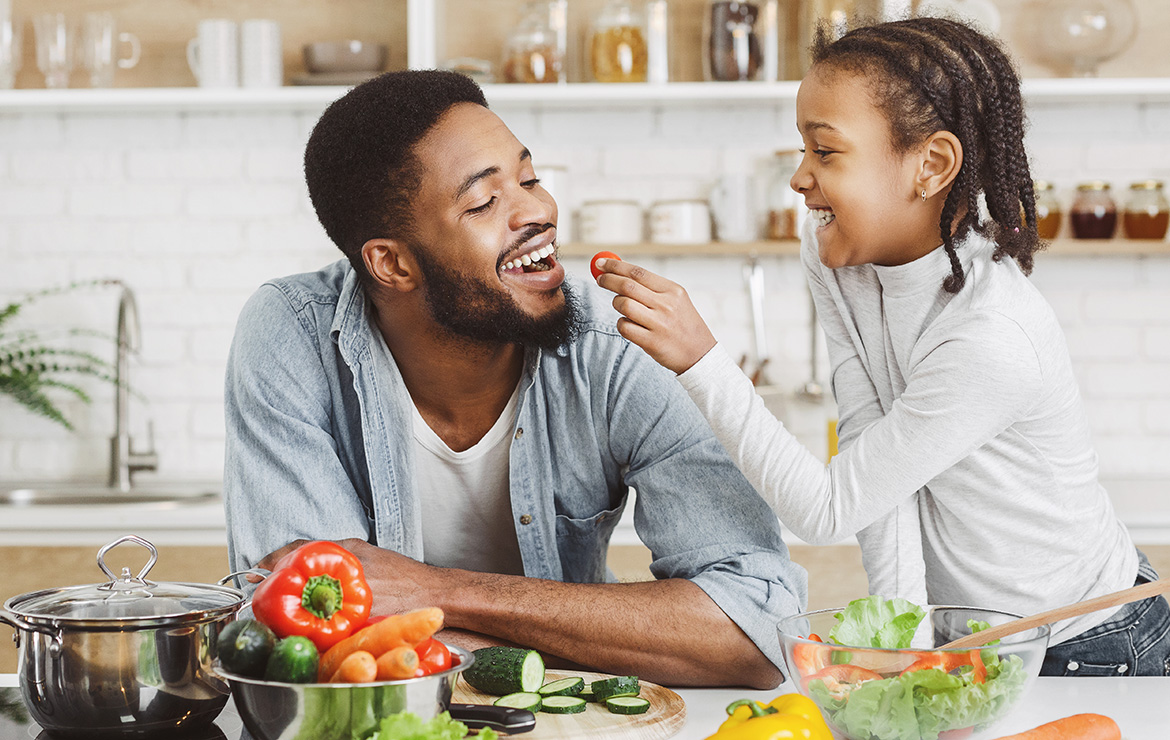 Girl feeding father a piece of vegetable