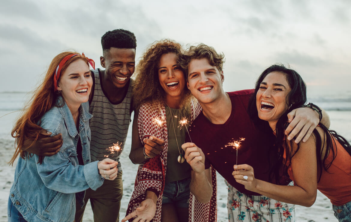 Group of friends holding sparklers at the beach