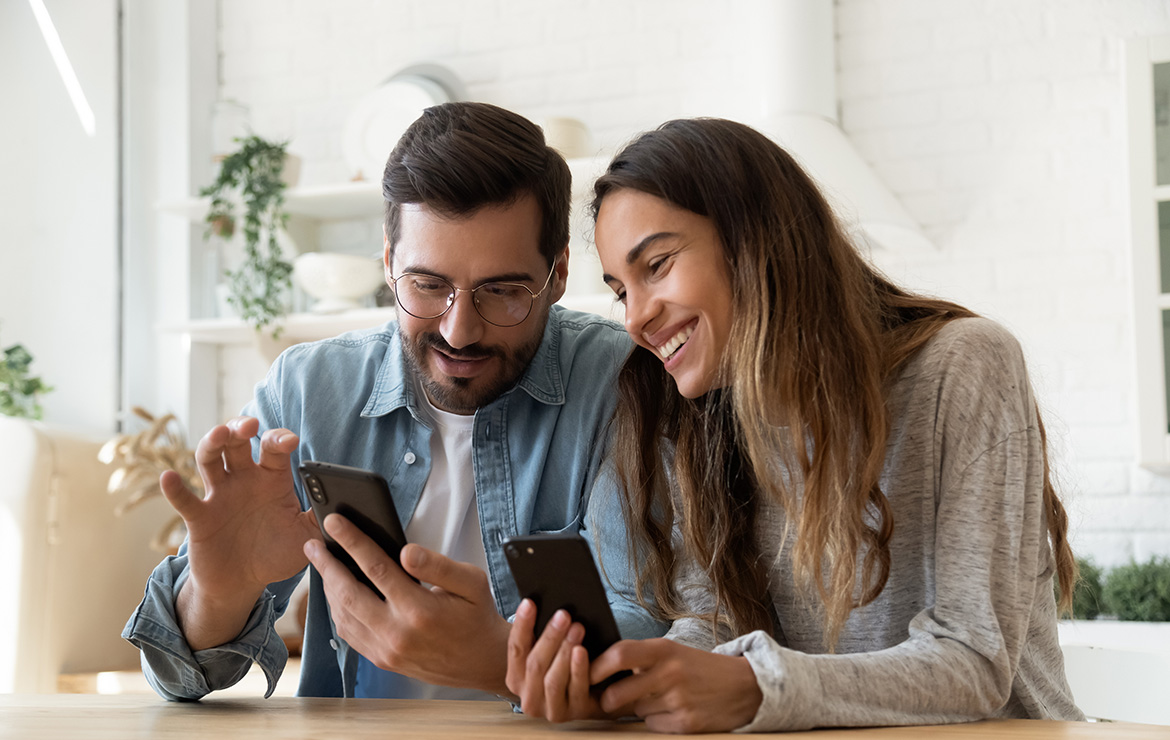 Man and woman smiling looking at smartphones