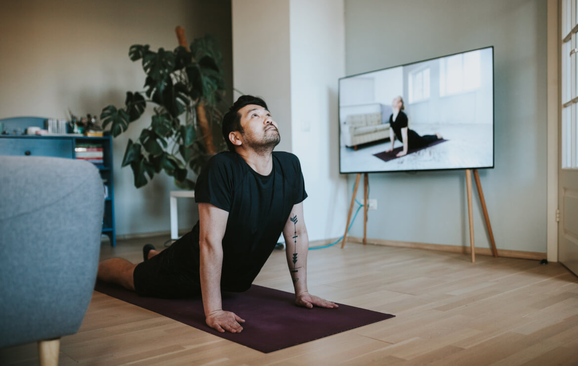 Man following yoga pose on mat in living r oom
