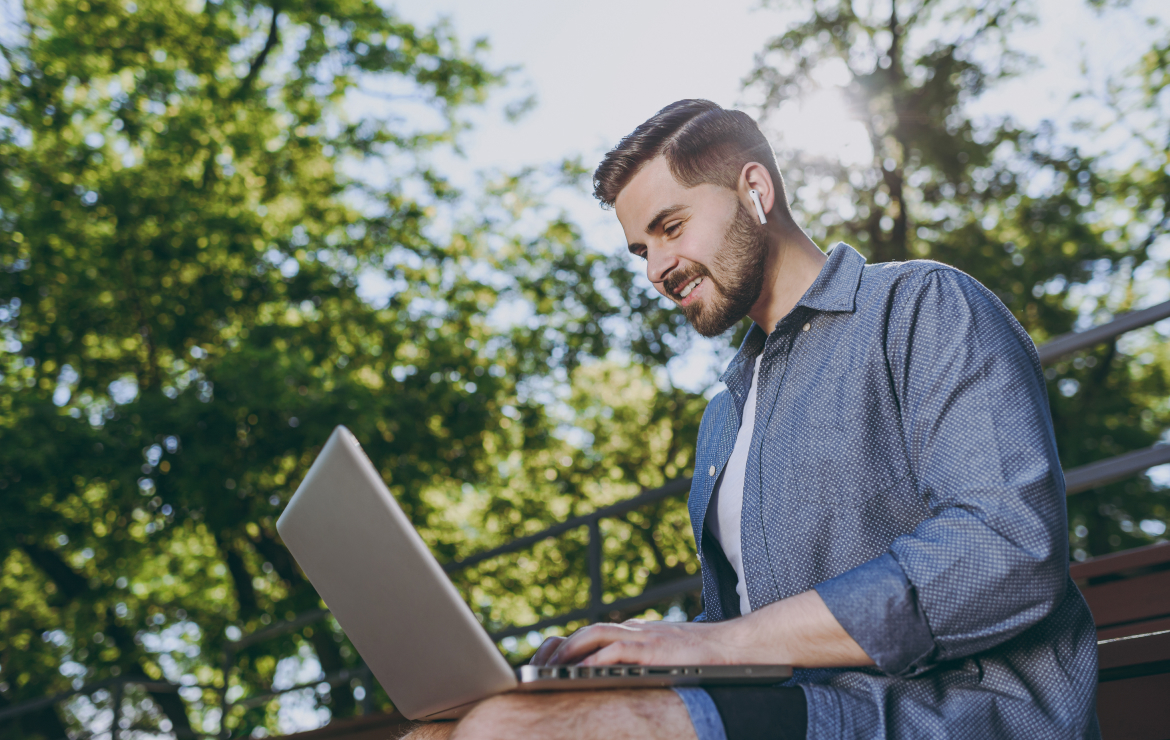 Man sitting in park typing on laptop