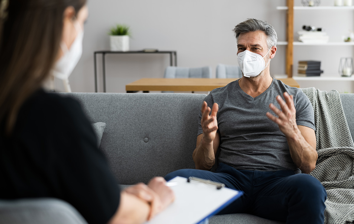 Man wearing facemask interacting with person