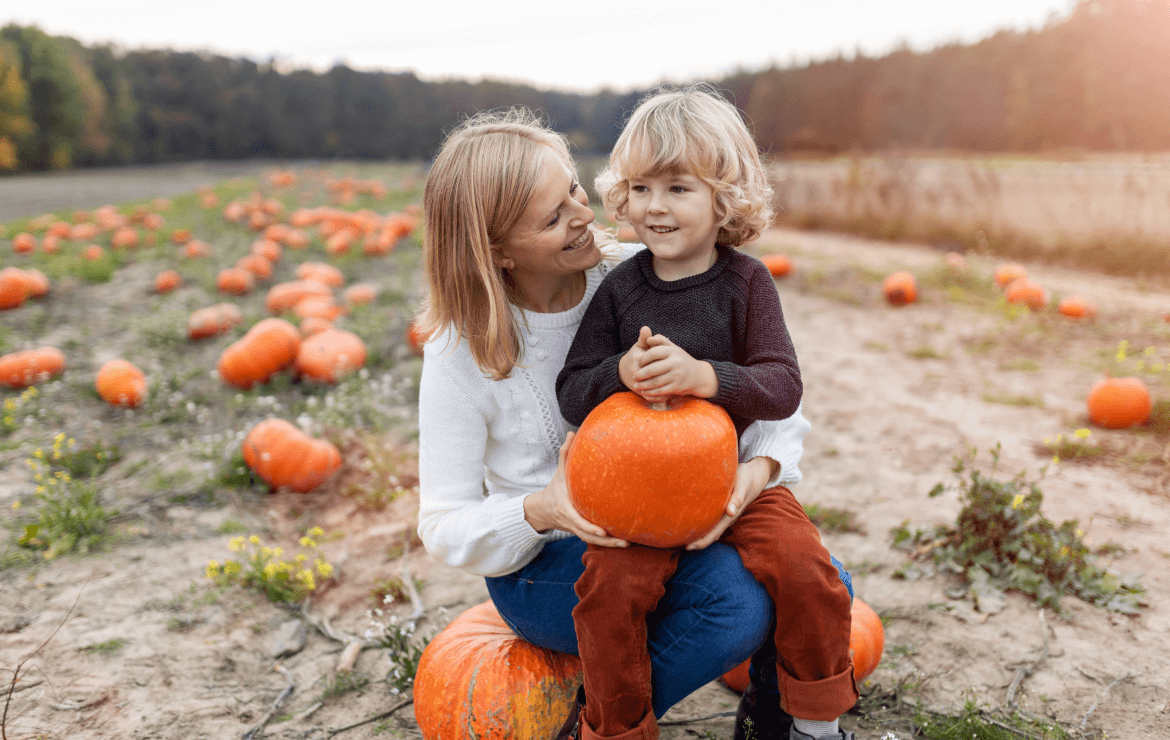 Mom and son sitting together in pumpkin patch