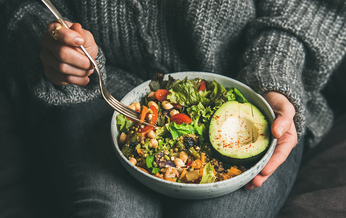 Person carrying a fork and bowl of salad