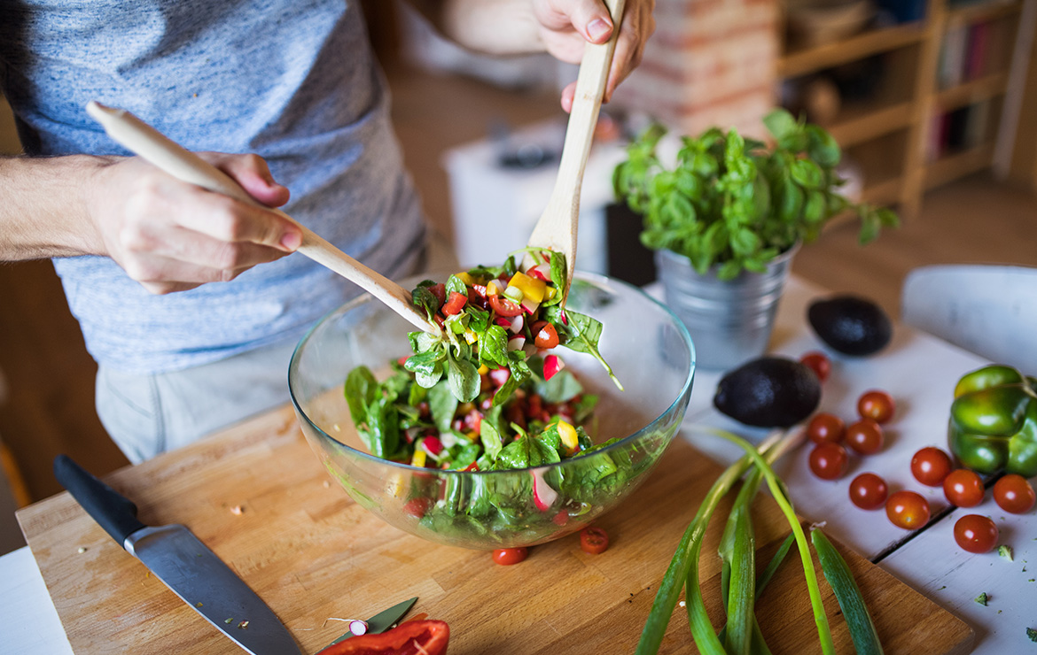 Person preparing salad within bowl