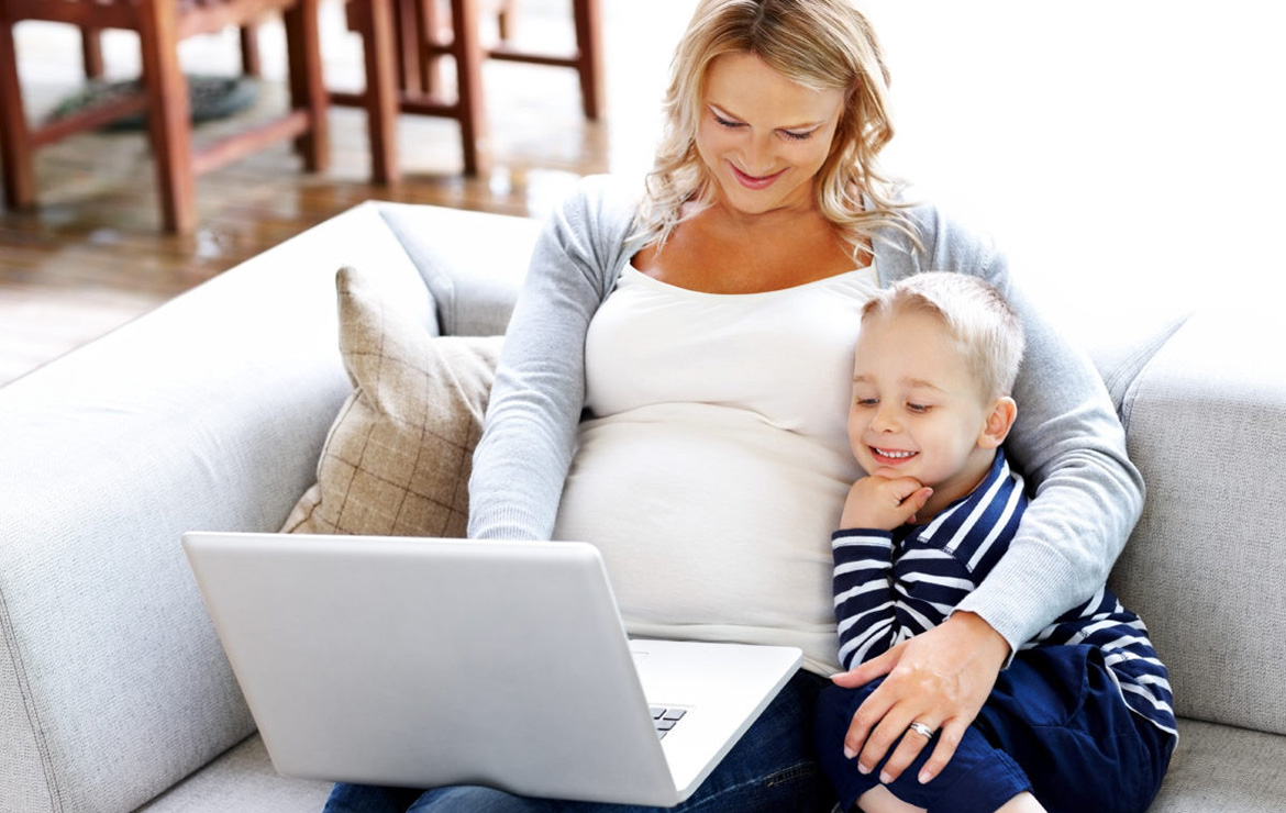 Pregnant mother with child viewing laptop together