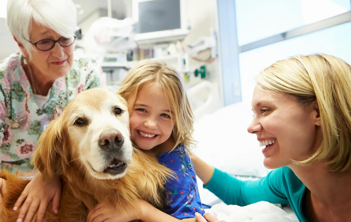 Smiling girl hugging dog with mom and grandma