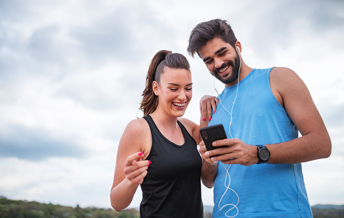 Smiling man and woman viewing phone after workout