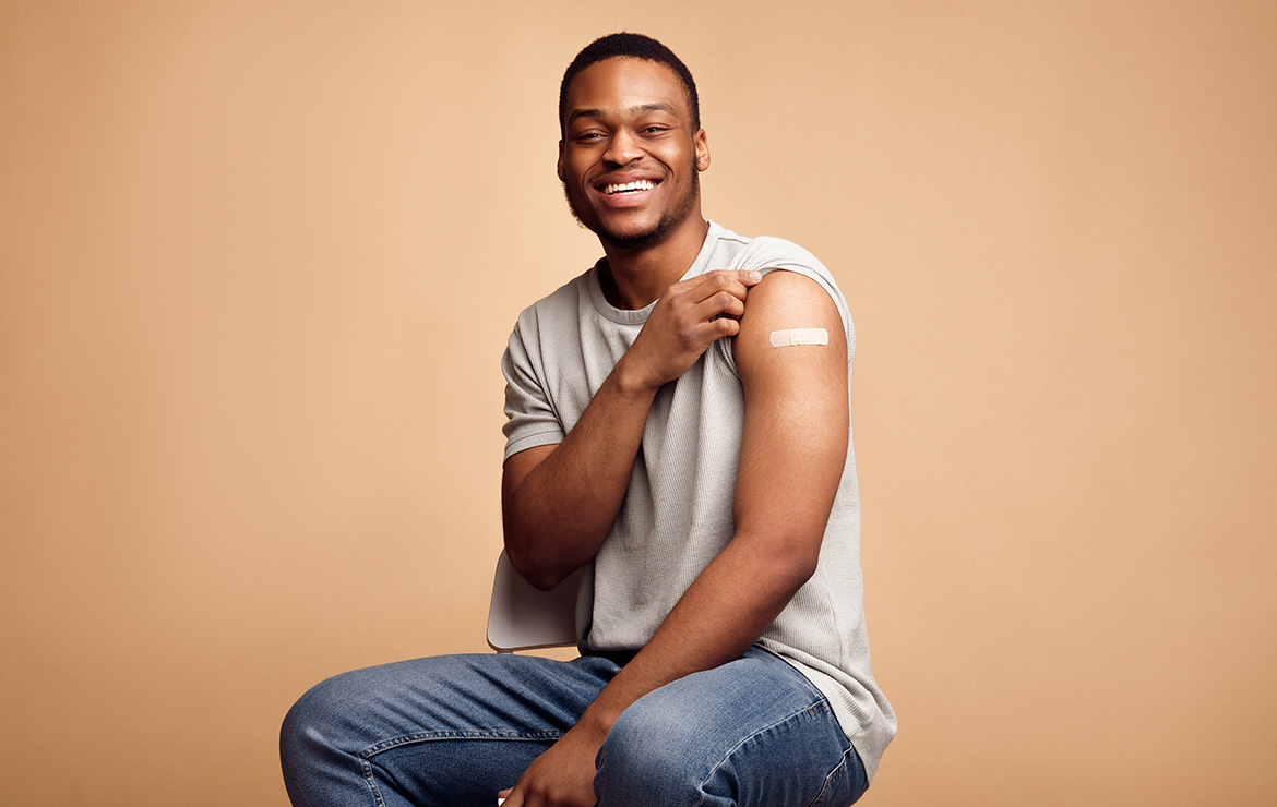 Smiling man showing band-aid in upper-left arm