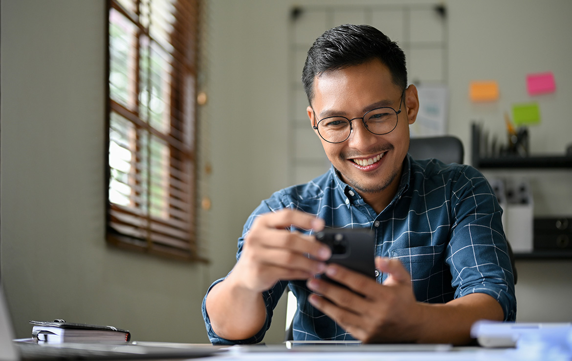 Smiling man sitting and using smartphone