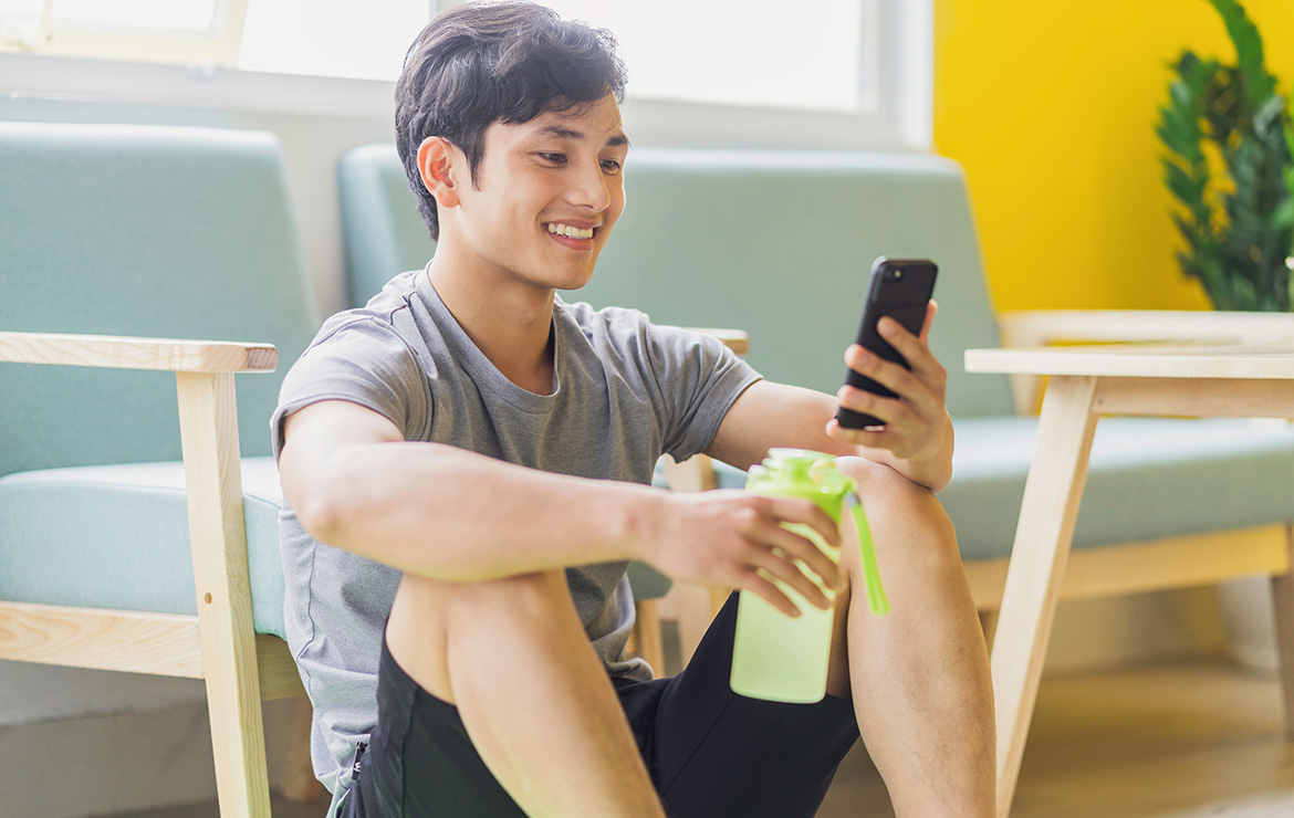 Smiling man sitting down looking at phone