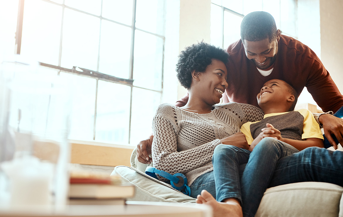 Smiling parents and child sitting in couch
