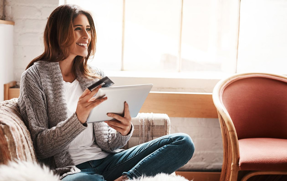 Smiling woman holding credit card and tablet