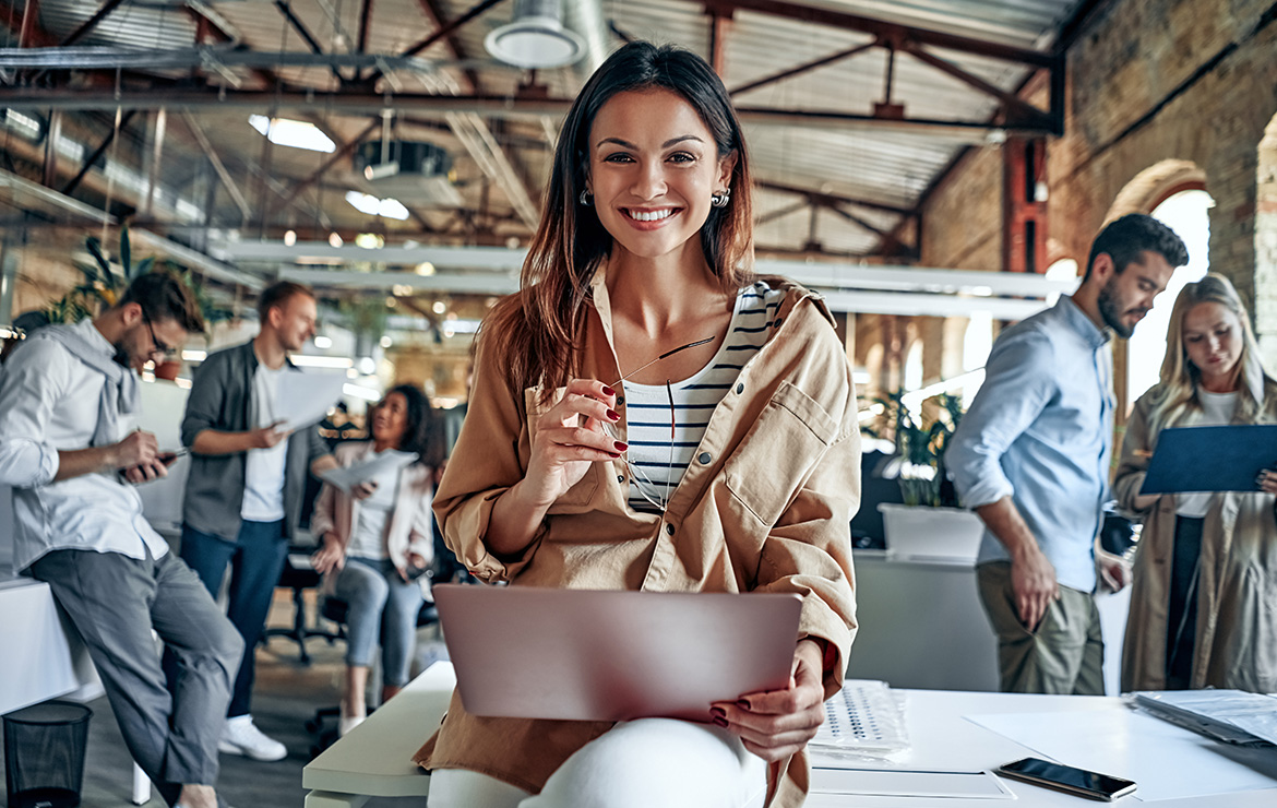 Smiling woman holding laptop at work