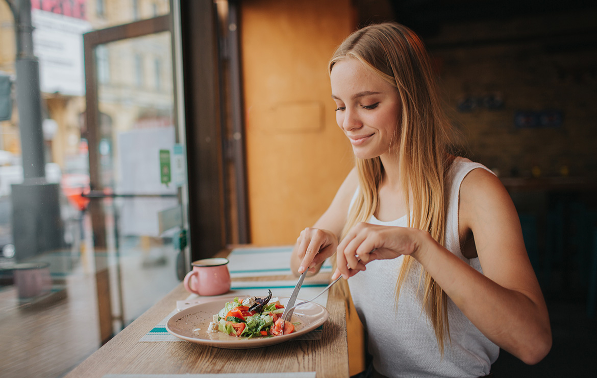 Smiling woman sitting down eating salad