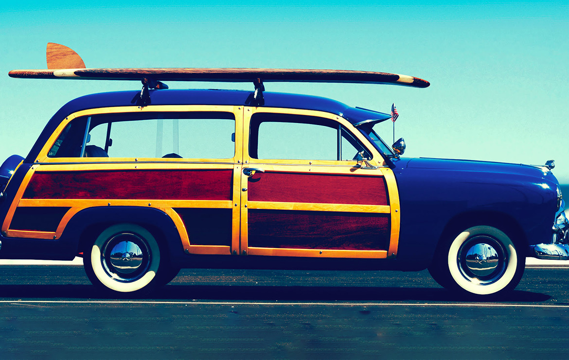 Surfboard on top of vehicle by beach