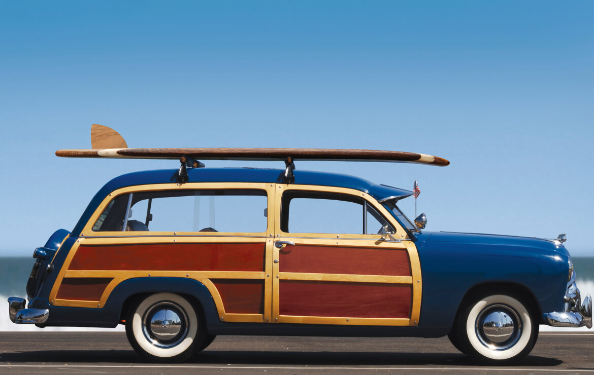 Surfboard on top of vehicle by beach