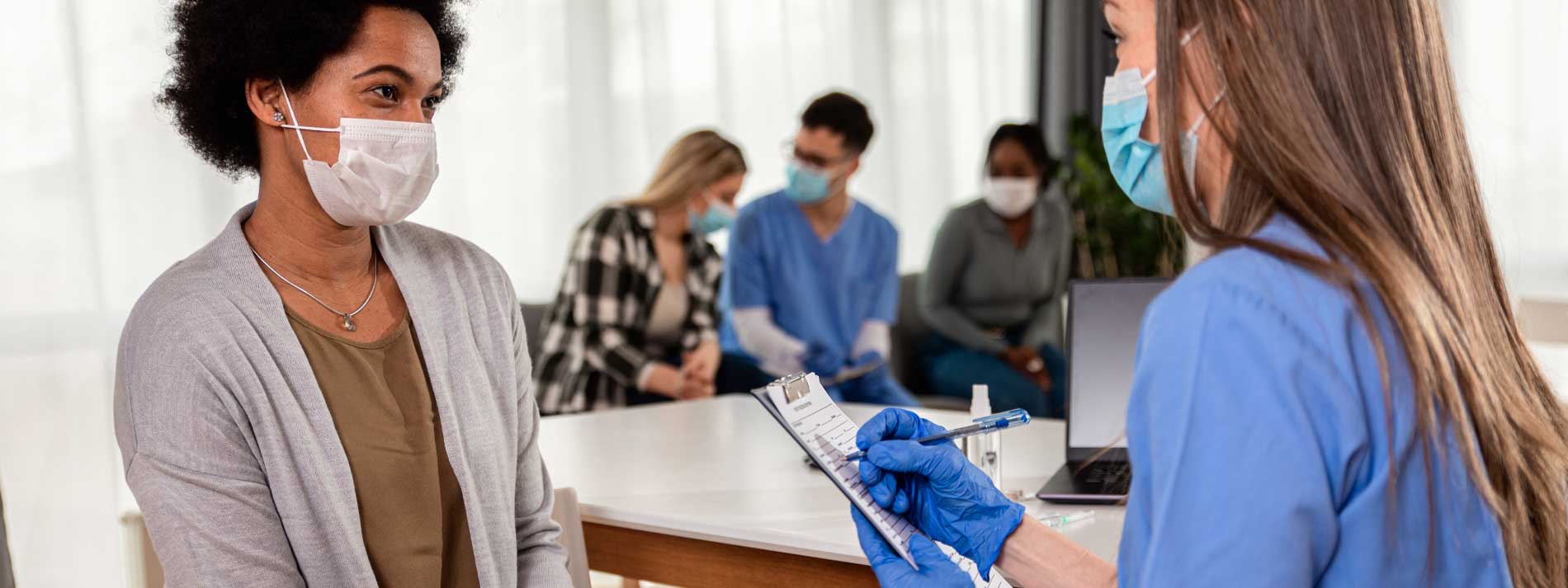 Woman-and-nurse-wearing-masks-sitting-together
