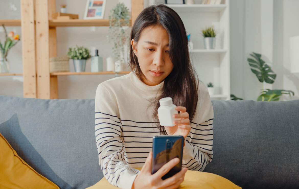 Woman holding up prescription bottle to mobile phone
