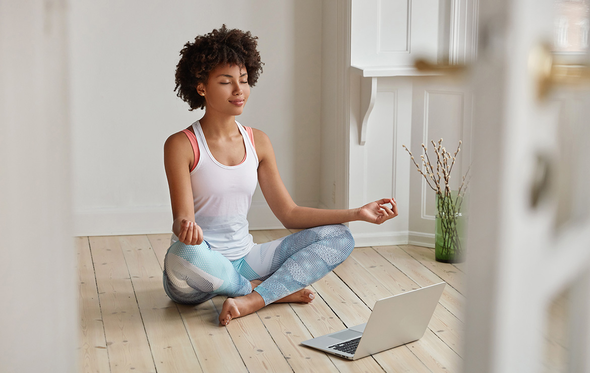 Woman meditating in front of laptop