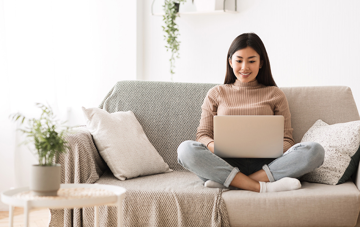 Woman sitting on couch using laptop