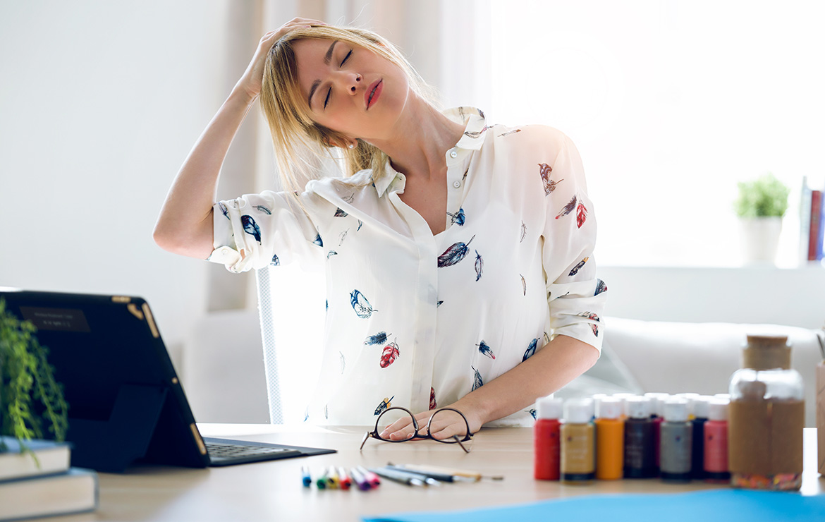 Woman standing in front of desk stretching neck