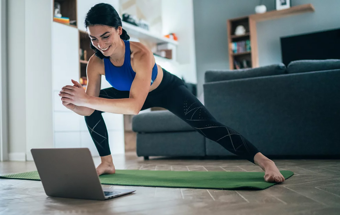 Woman stretching while watching laptop