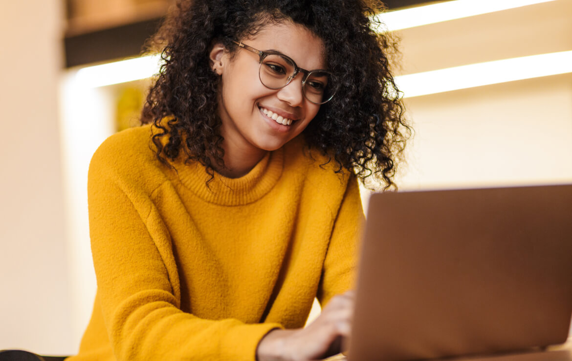 Woman wearing glasses smiling while using laptop