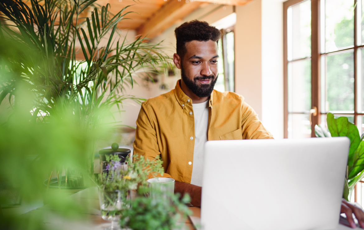 Young man typing on laptop inside home office