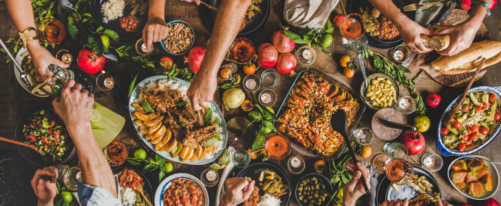 Hands reaching for food across dinner table