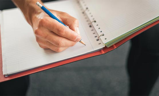 man writing in notebook