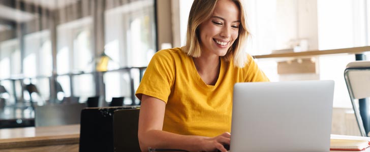 Woman smiling while typing on laptop