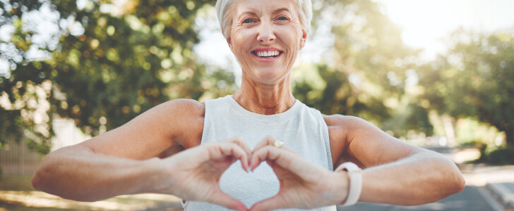 Portrait of woman holding up heart sign